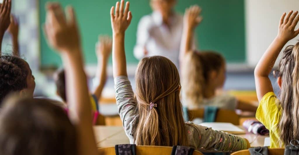 Elementary Students raising hands in a classroom